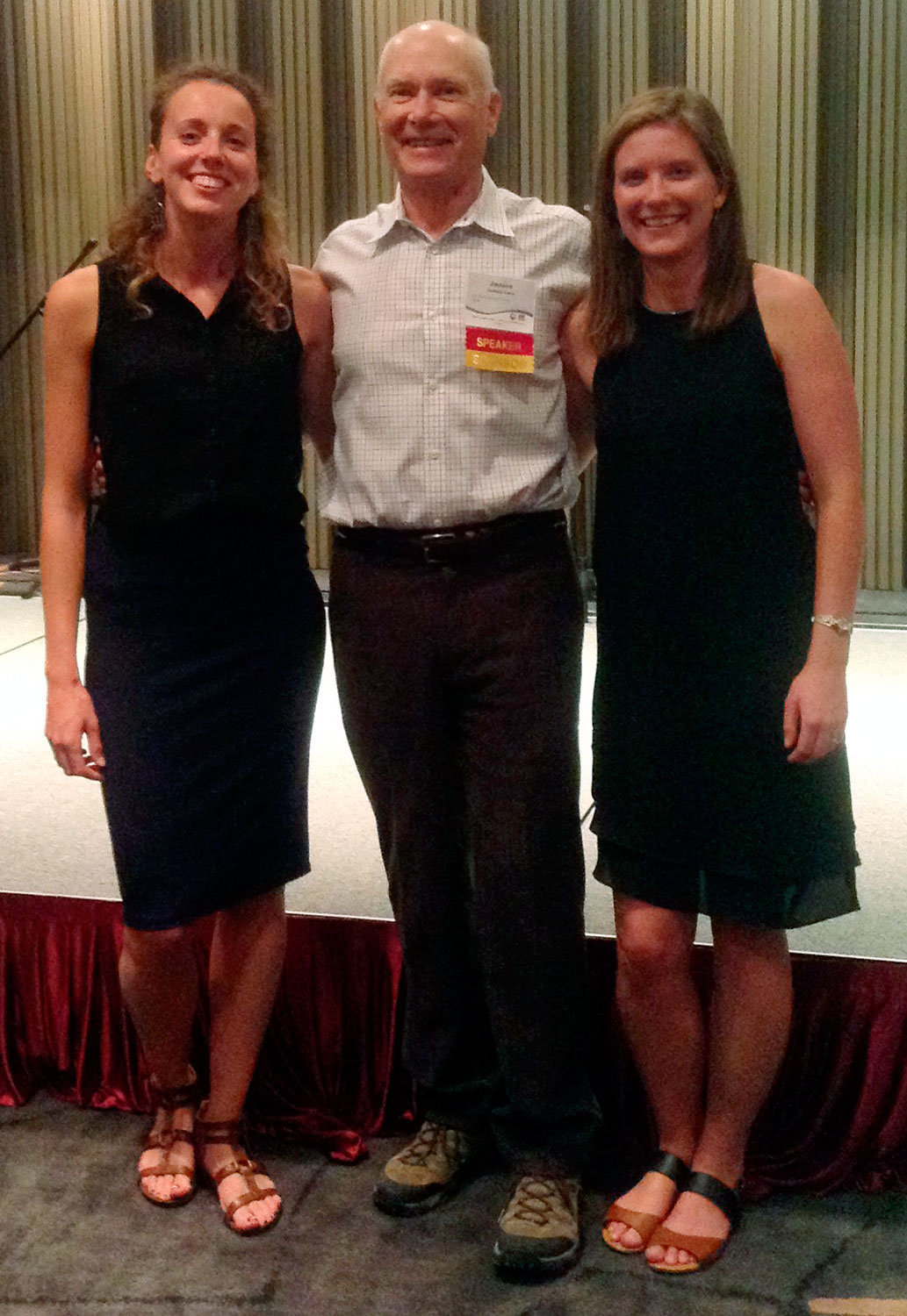 A man stands between two women, everyone smiling for the camera.